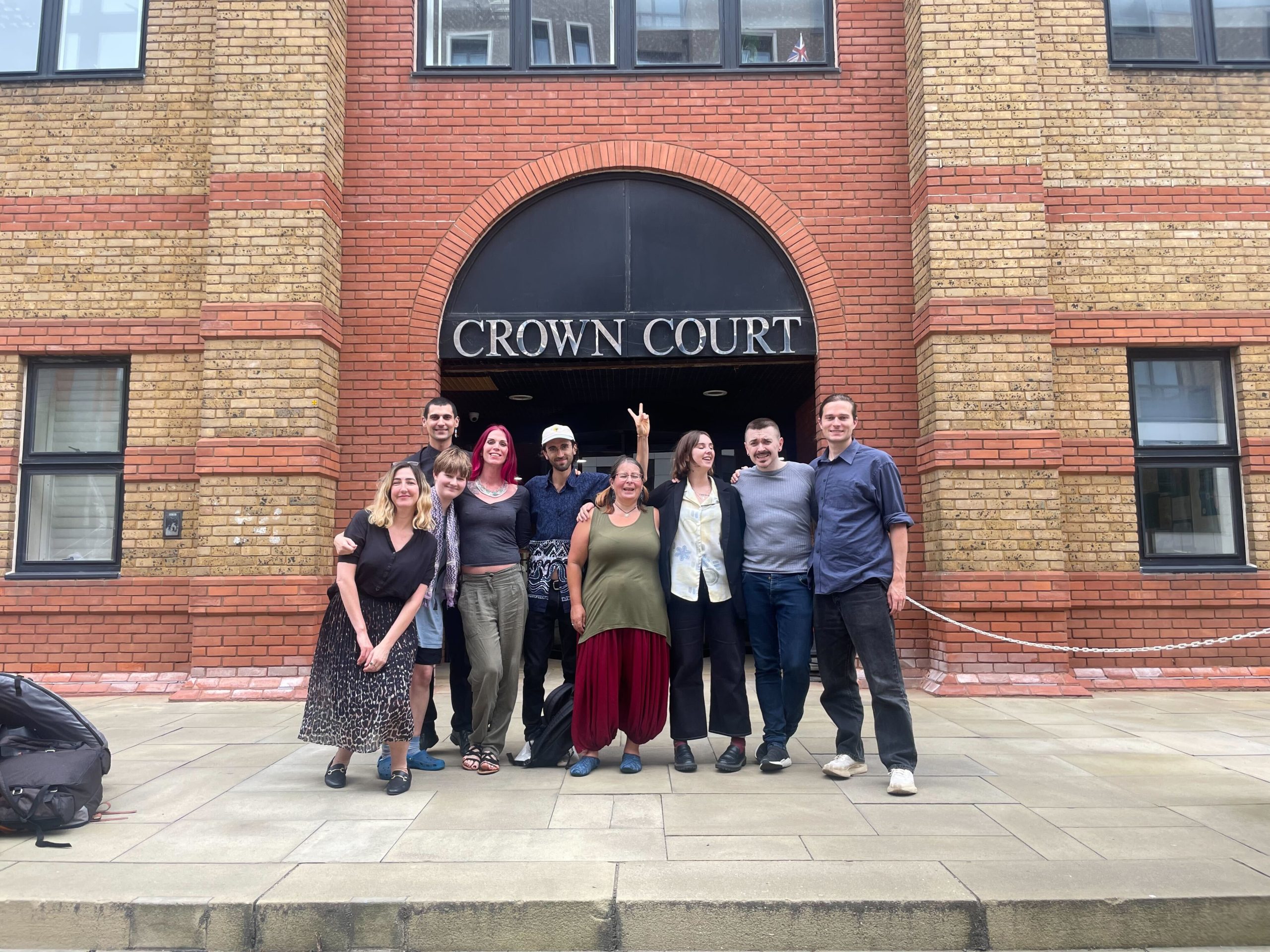 A group of people outside a Crown Court building, looking happy