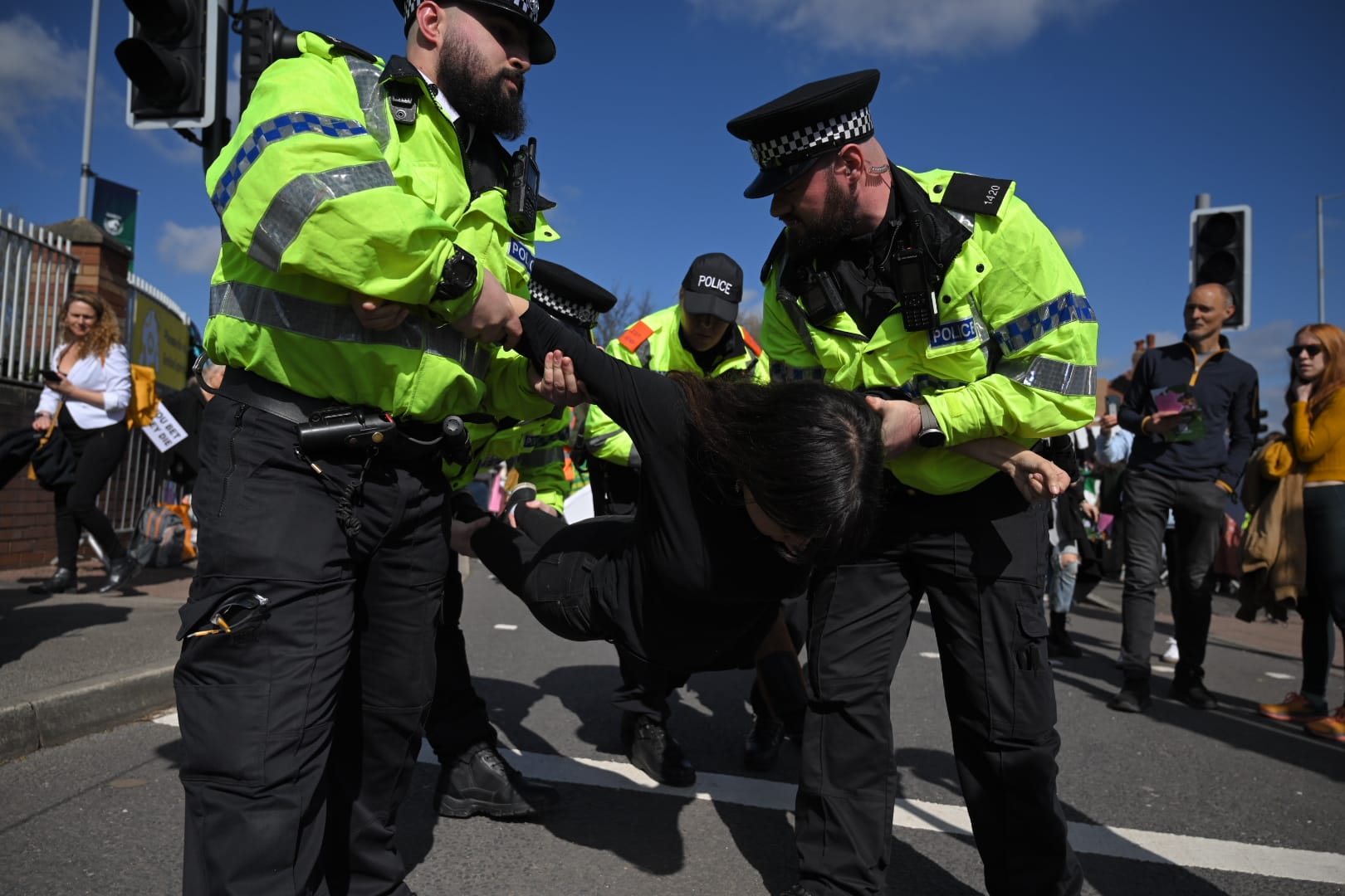 A female protester wearing black is carried by four police officers