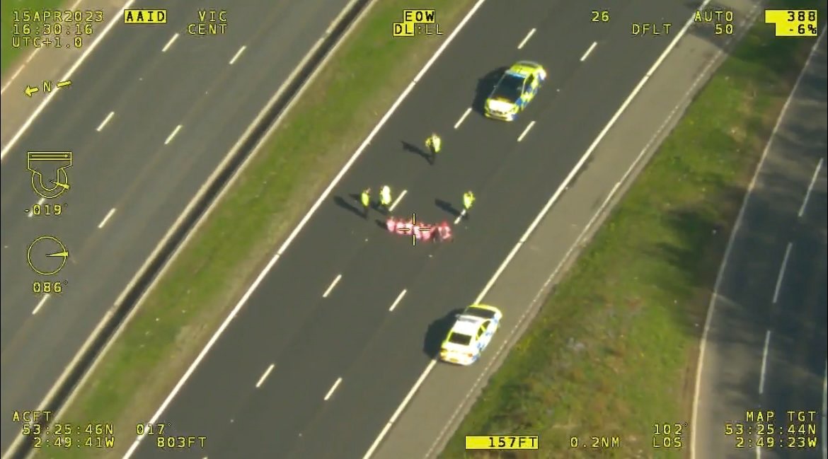 A still from police helicopter footage showing the seven Animal Rising supporters sat down and glued on to the M57