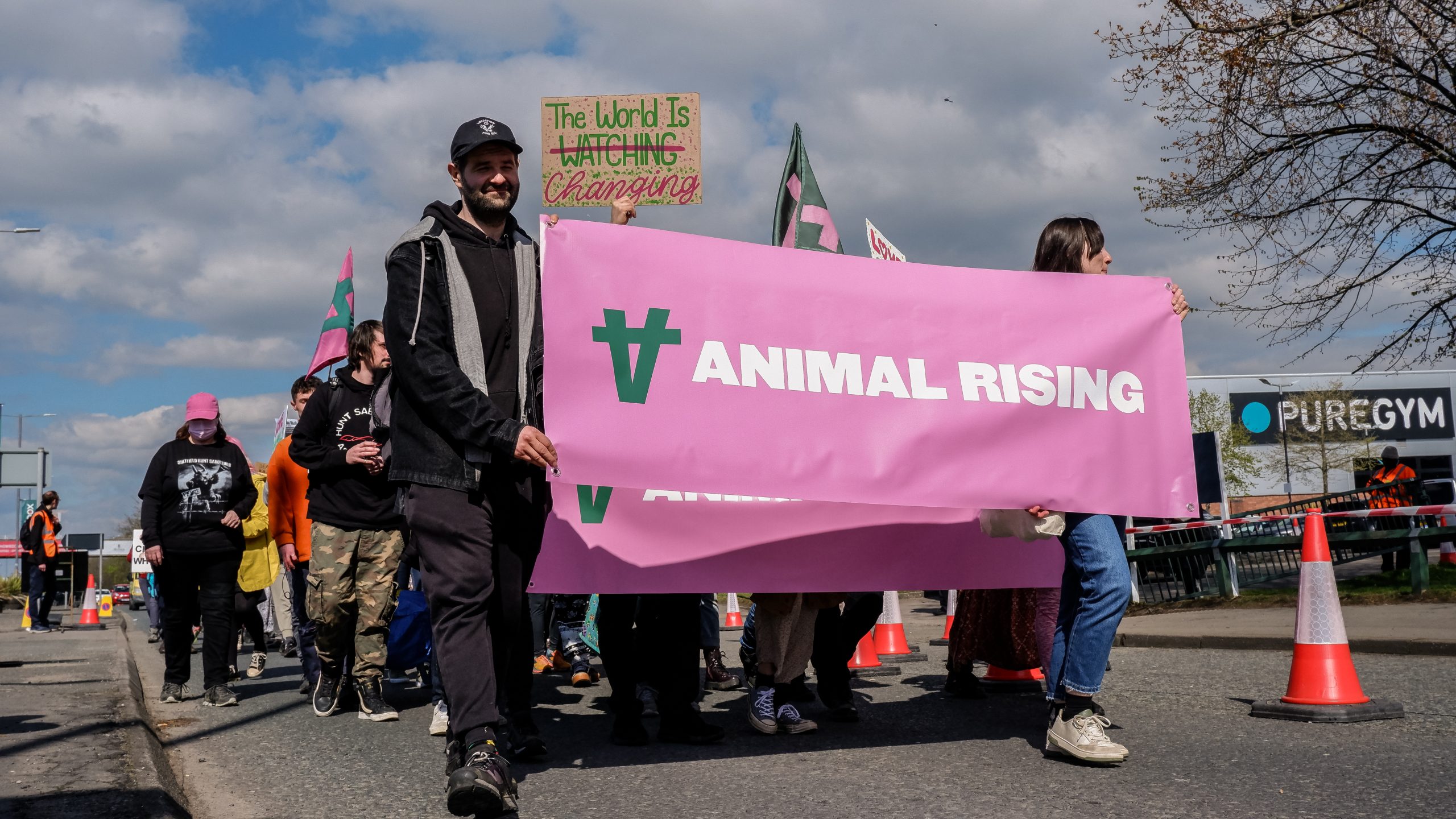 Campaigners peacefully march while holding a pink banner which reads "Animal Rising"